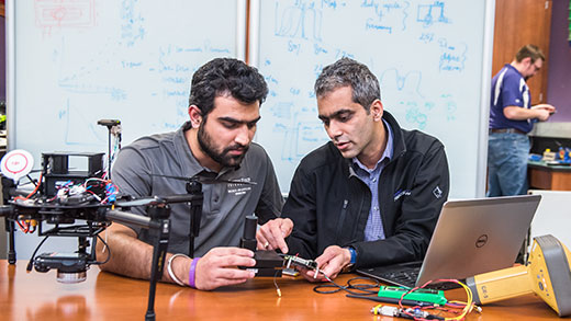 Two men sitting at table looking at infrared camera and sensor Two men sitting at table looking at infrared camera and sensor