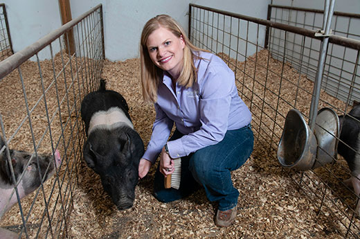 Woman kneeling next to pig, Cassie Jones