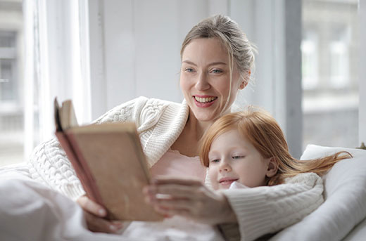mother and daughter reading on a couch