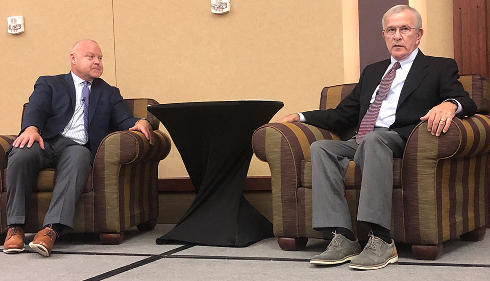 two men sitting in lounge chairs on stage, Nevil Speer and Mike Johanns two men sitting in lounge chairs on stage, Nevil Speer and Mike Johanns