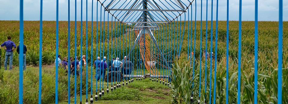 Long view of a center pivot sprinkler, with orange hoses hanging toward the ground Long view of a center pivot sprinkler, with orange hoses hanging toward the ground