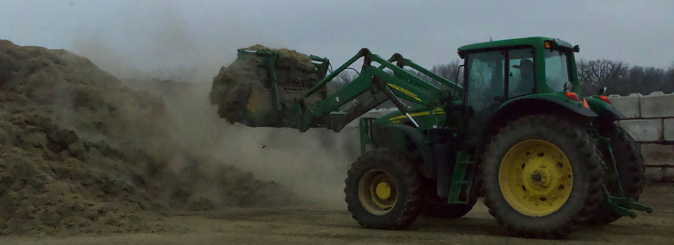 Tractor loading dirt onto pile