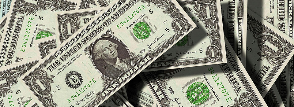 Closeup of many dollar bills spilled out onto a tabletop