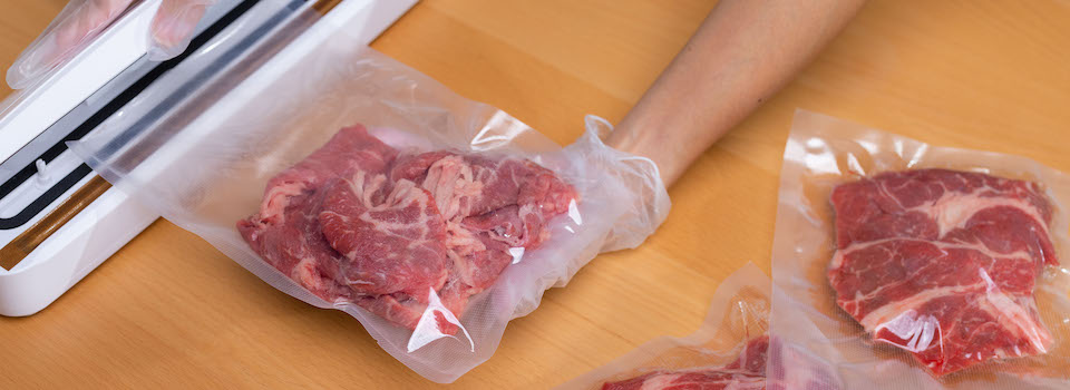 A woman vacuum sealing meat. A woman vacuum sealing meat.