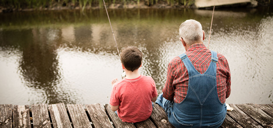 Man and child sitting on dock with fishing poles