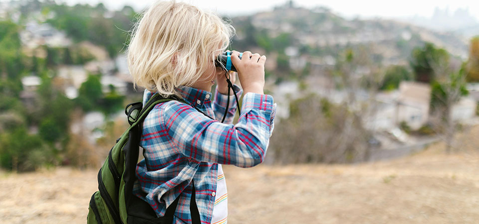 Side view of young boy looking through binoculars