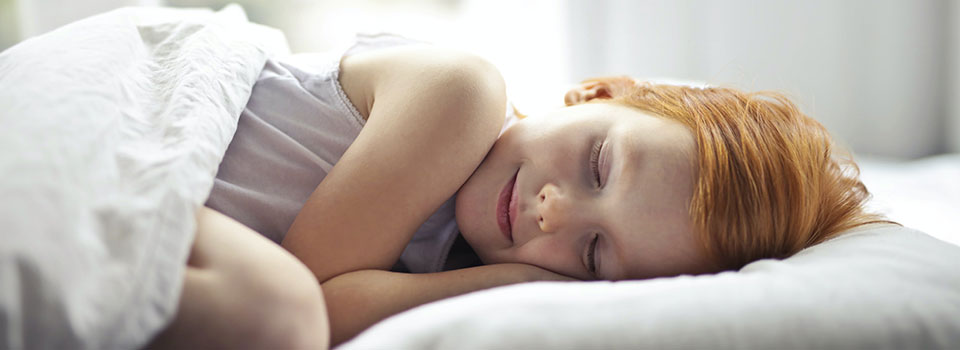 Girl with red hair sleeping on white pillow