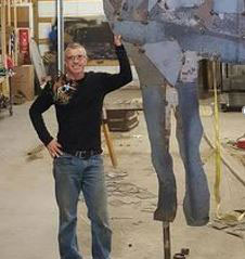 Man standing next to large metal sculpture