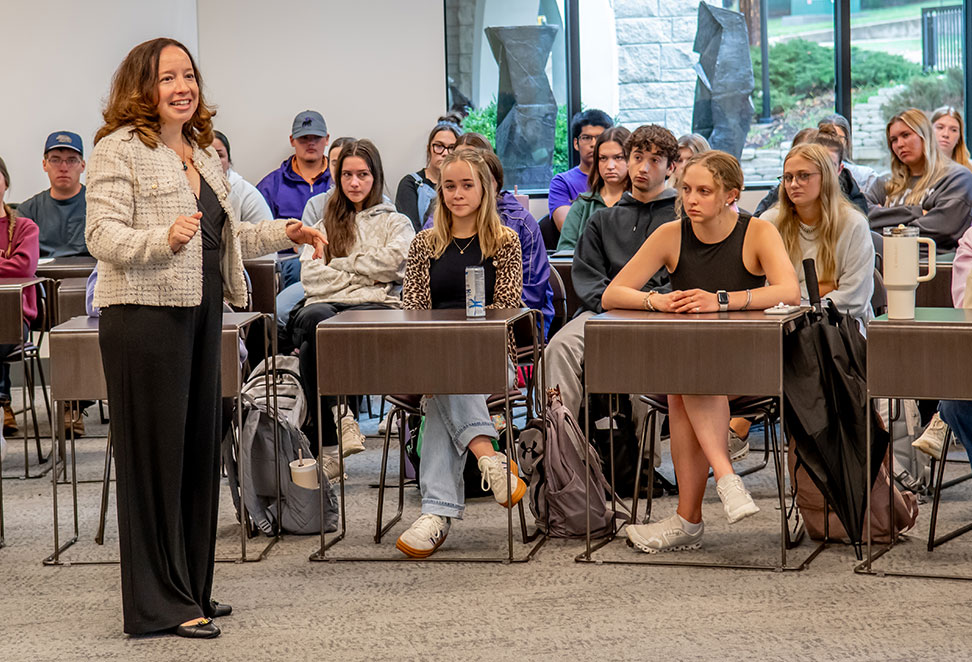 Woman standing in front of attentive students in a modern classroom with large windows in the background Woman standing in front of attentive students in a modern classroom with large windows in the background