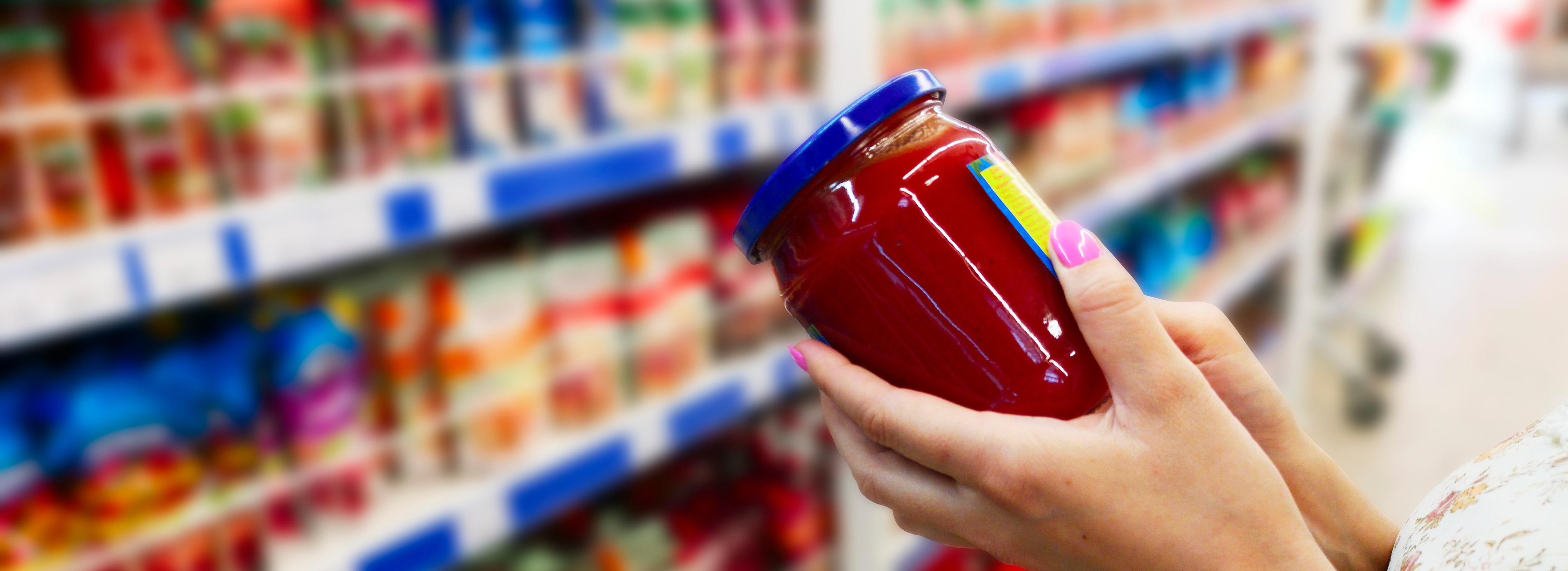 Woman holding jar of salsa in grocery store