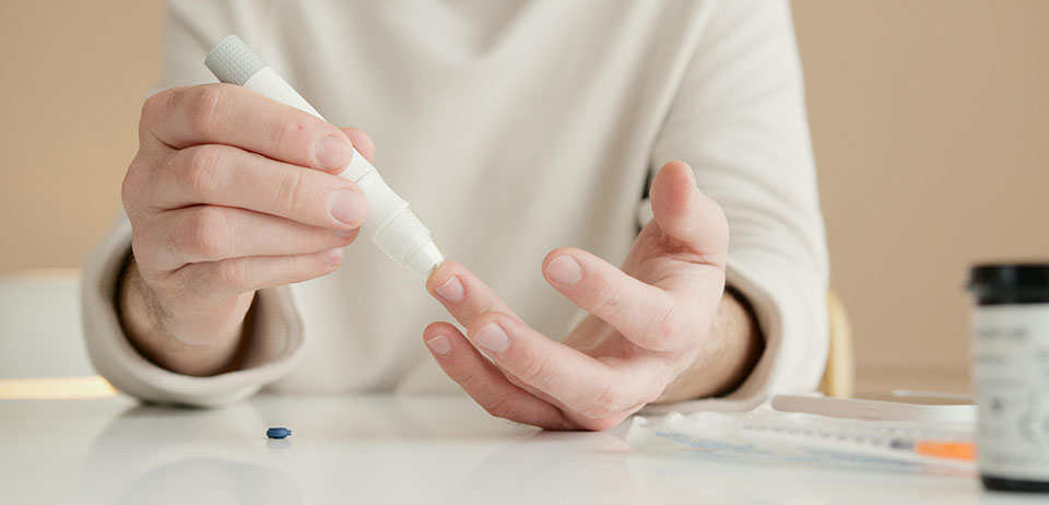 closeup of woman's hands, pricking a finger to test blood sugar level