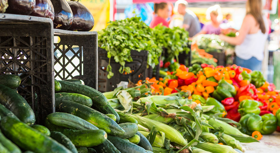 near view of vegetable stand at the farmers market, customers blurred in background