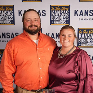 Man in orange shirt and woman in maroon dress posing for camera