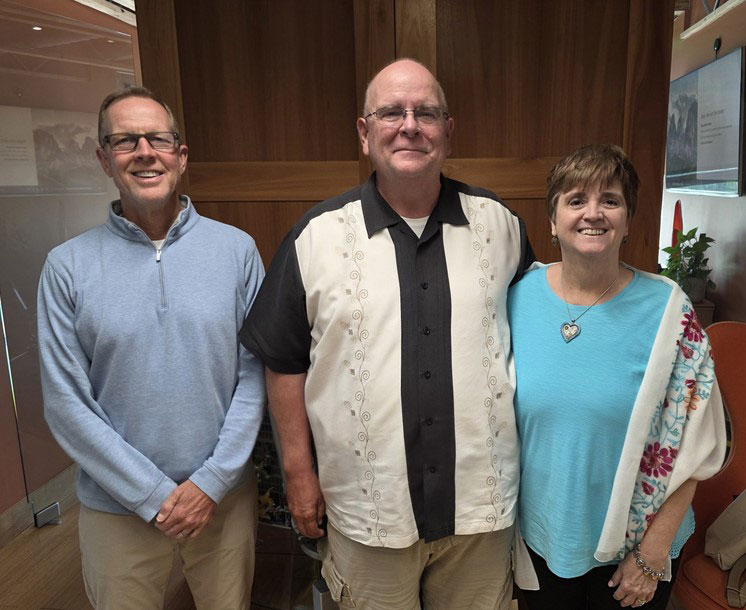 Three people standing and looking toward camera