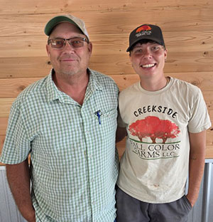 Man and woman wearing ball caps standing in front of wooden wall