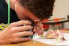A 4-H students looks through a magnifier at parts of a flower during a science demonstration during 2019 4-H Discovery Days.