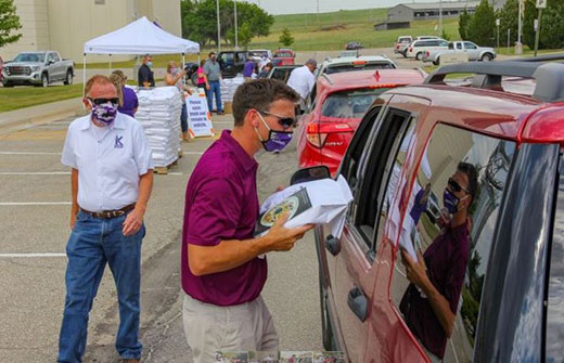 Man handing bag of flour to person in car