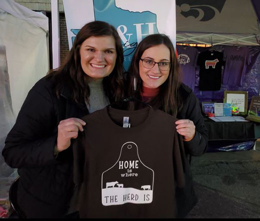 Two women smiling and holding t-shirt, C&H Designs