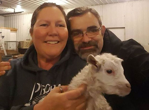 Woman and man holding a small white goat