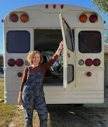 Woman standing at back door to white school bus