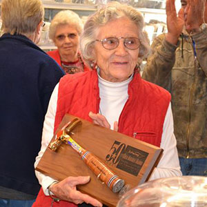 Woman with eyeglasses holding plaque with hammer attached