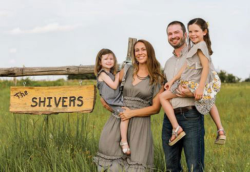 Man and woman with two daughters, standing near farm field Man and woman with two daughters, standing near farm field