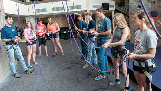 Students tying ropes, climbing wall