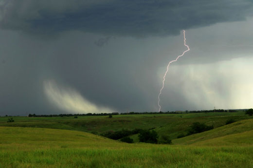 Lightning in distance, green Kansas prairie in foreground