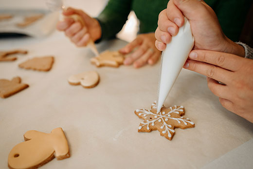 closeup of hands decorating christmas cookies