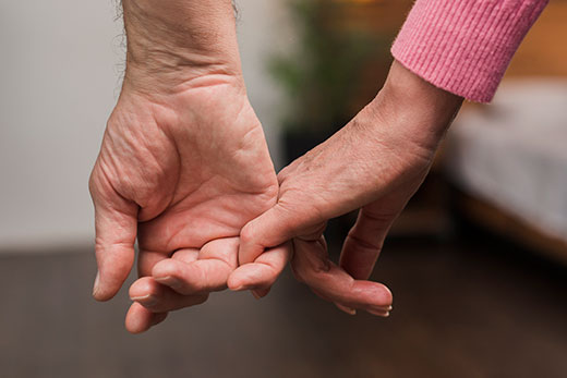 closeup of two hands holding, elderly couple