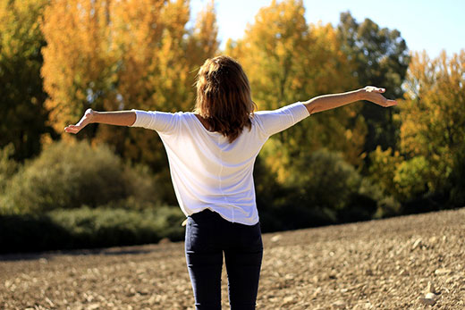 woman with outstretched arms looking at fall colors