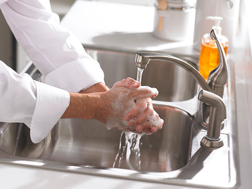 closeup of person washing hands in kitchen sink