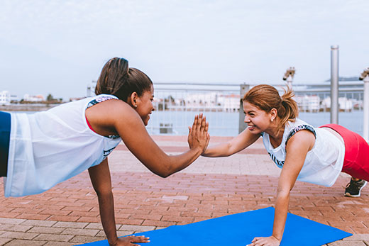 Two women slapping hands while doing pushups