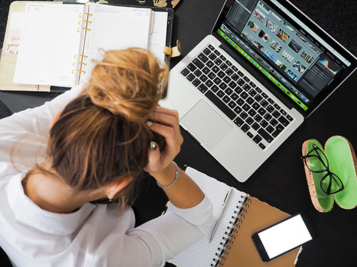 Woman clutching head while sitting at work desk Woman clutching head while sitting at work desk