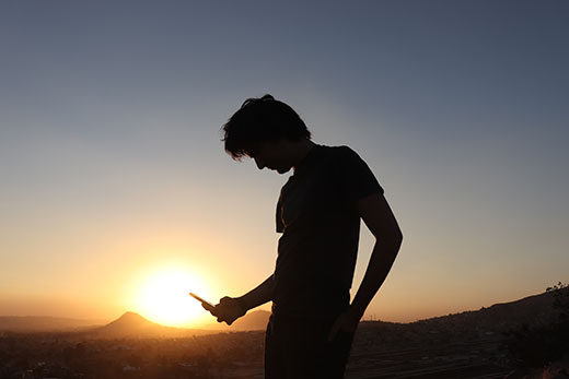silhouette of young adult looking at phone