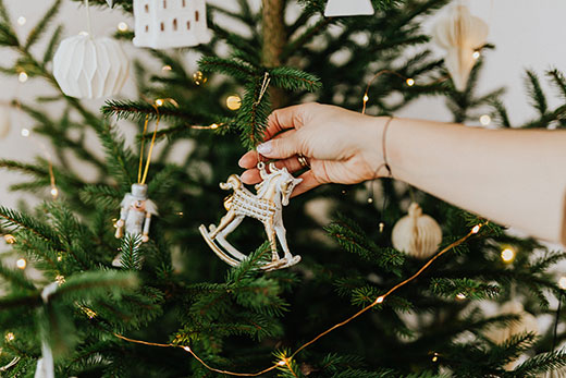 closeup of woman's hand placing ornament on Christmas tree