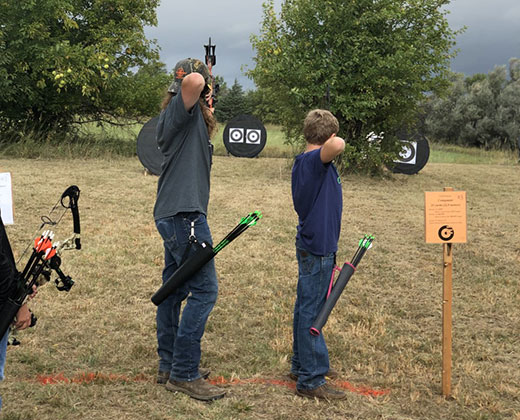 Two boys shooting bows at targets