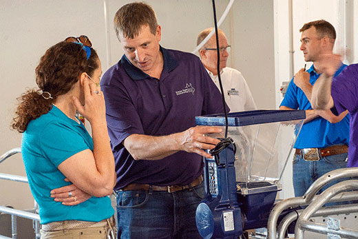 Man standing near drop feeder talking with woman