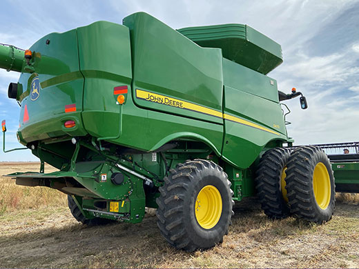 Green tractor with roller cage mill attached to back end