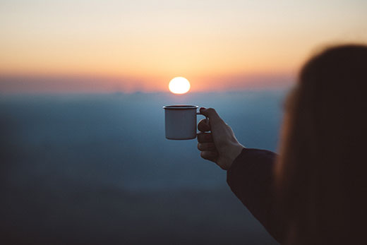 silhouette of woman holding cup of coffee toward sunrise silhouette of woman holding cup of coffee toward sunrise