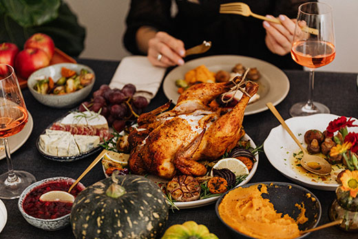 roasted turkey on table surrounded by many side dishes