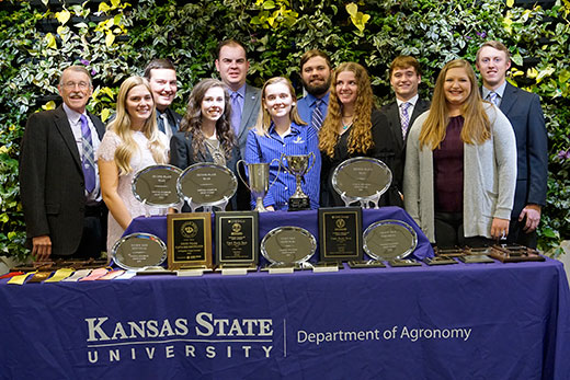 members of k-state crops team standing behind table with trophies