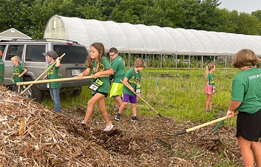 Kids with garden implements working in soil and compost