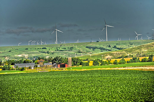 Farm in foreground with many wind turbines across Kansas prairie