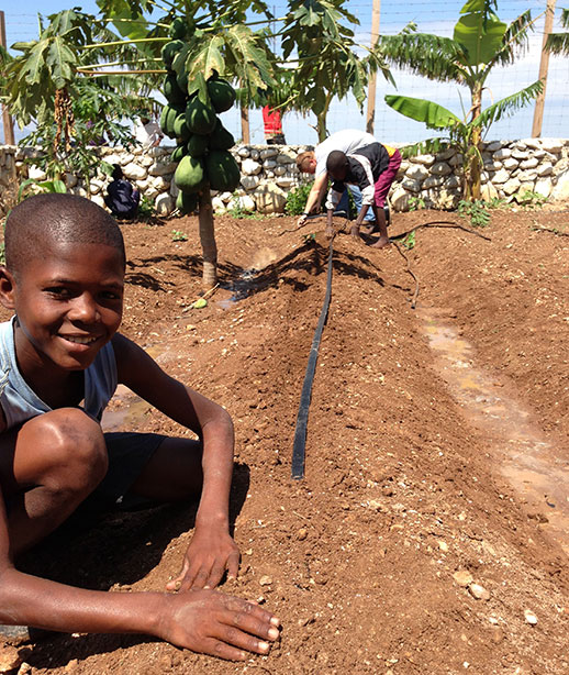 young haitian boy with hand in dirt