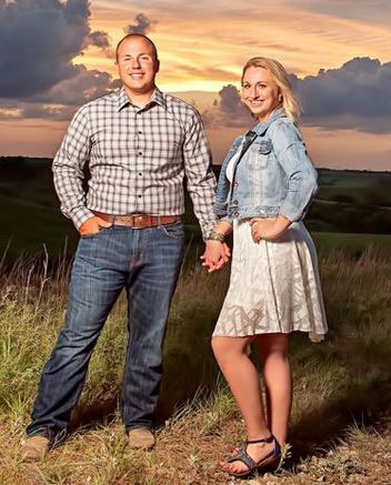 man and woman standing with kansas sunset in background