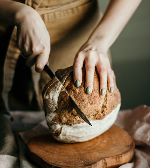 woman's hands shown cutting yeast bread