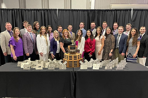 Group photo, K-State meat animal evaluation team with numerous trophies set on table