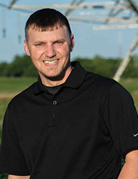 Man smiling in black shirt, outdoors