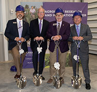 Four men holding shiny silver shovels, K-State agronomy groundbreaking
